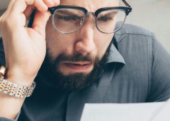 Persona revisando facturas impagadas preocupada por aparecer en el fichero de morosos ASNEF