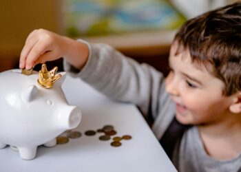 Niño introduciendo monedas en una hucha aprendiendo educación financiera para hijos en casa