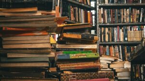 Pila de libros de finanzas personales en una biblioteca como recurso para aprender a invertir