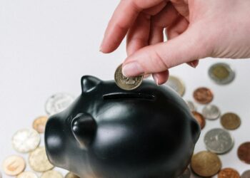 Persona depositando una moneda en una hucha, simbolizando el ahorro para el plan de pensiones en España