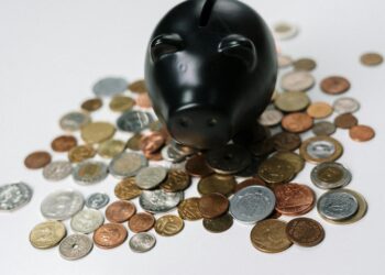 Hucha negra rodeada de monedas representando el interés compuesto y el ahorro a largo plazo