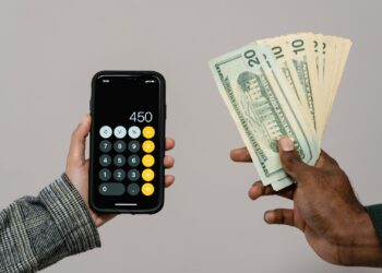 Persona calculando su patrimonio neto personal con calculadora y documentos financieros