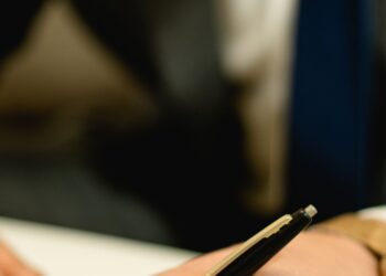 Persona firmando documentos de una herencia ante notario para liquidar el impuesto de sucesiones