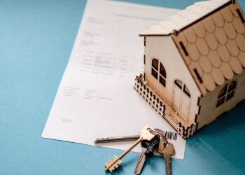 Contrato, llaves y maqueta de casa sobre una mesa que ilustran la subrogación de hipoteca