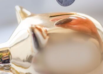 Persona introduciendo una moneda en una hucha, imagen sobre cuánto ahorrar al mes según edad e ingresos