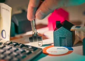 Llaves y calculadora sobre documentos para calcular los impuestos por vender una casa