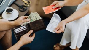 Persona revisando facturas y recibos de domiciliación bancaria sobre una mesa con calculadora