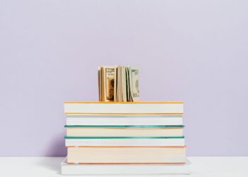 Billetes sobre una pila de libros que ilustran los mejores libros de economía para entender la actualidad