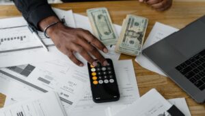 Persona calculando su ratio de endeudamiento con una calculadora sobre documentos financieros