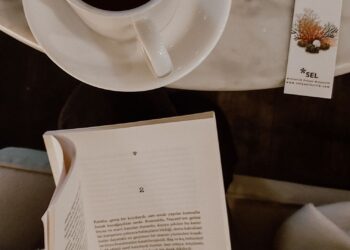 Persona leyendo un libro con una taza de café, imagen de apoyo para los mejores libros de psicología del dinero