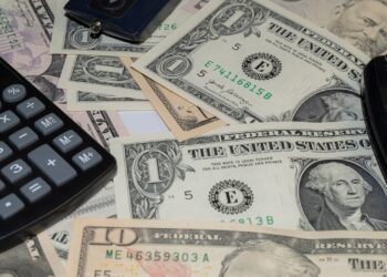 Llave de coche, billetes y calculadora para calcular cuánto cuesta tener un coche al año