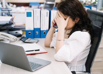Mujer revisando documentos mientras atiende una llamada de una empresa de recobro
