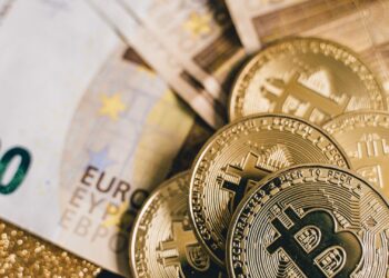 Billetes de euro junto a monedas de bitcoin al vender criptomonedas y pasar el dinero al banco