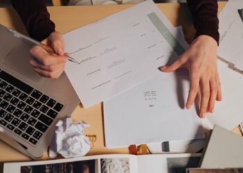 Persona tramitando el certificado digital con un portátil y documentos sobre la mesa
