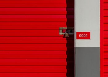 Puerta metálica roja de un trastero con candado, ejemplo de invertir en trasteros